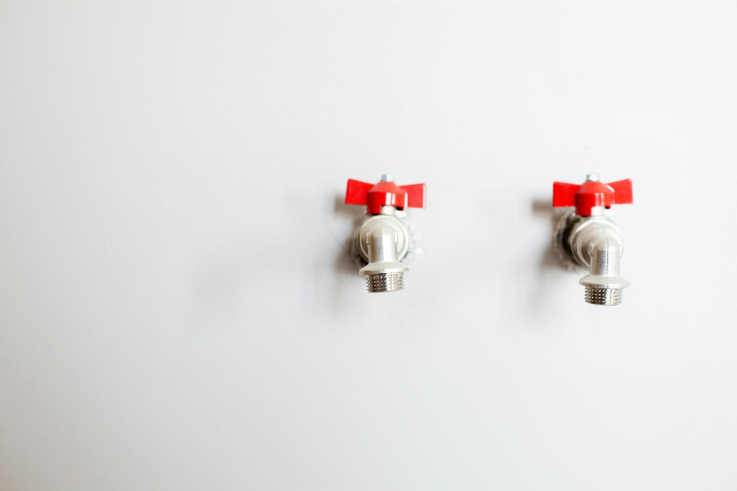 Two red taps on a white wall